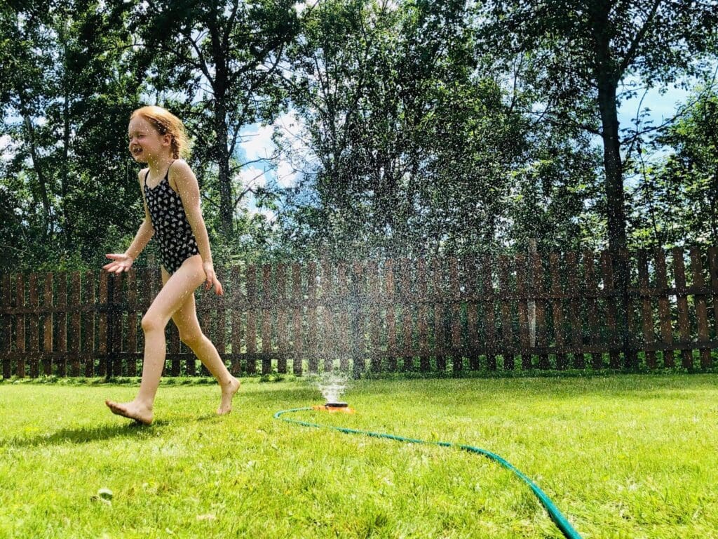 little girl running through sprinkler